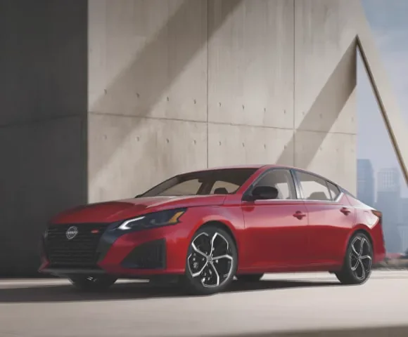 Red 2027 Nissan Altima midsize AWD sedan 3/4 profile view, parked in a well-lit garage at Ricart Nissan in Groveport OH